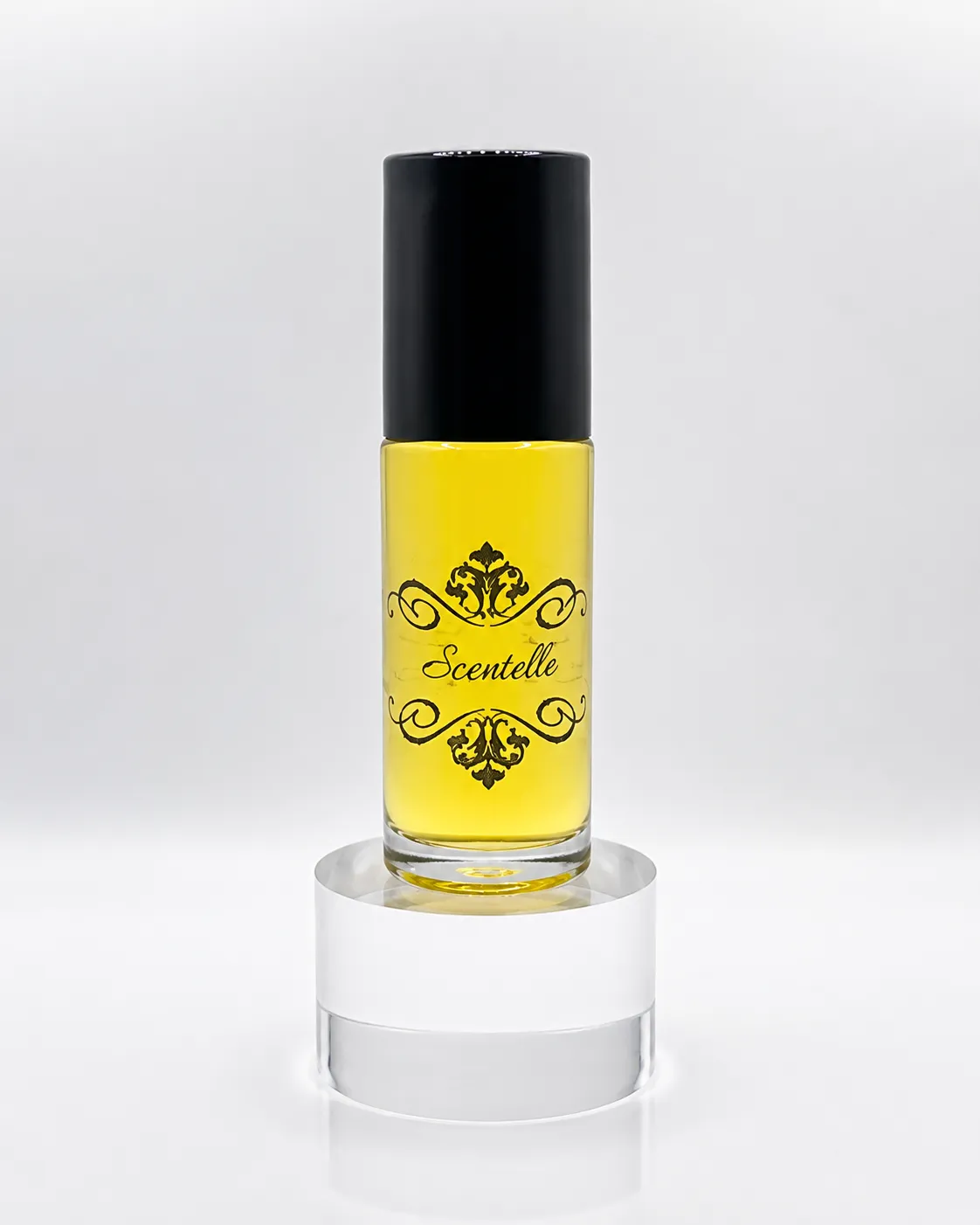 Scentelle 1 oz roll-on perfumed body oil in a thick glass bottle with yellow liquid, a black cap, and an ornate logo.